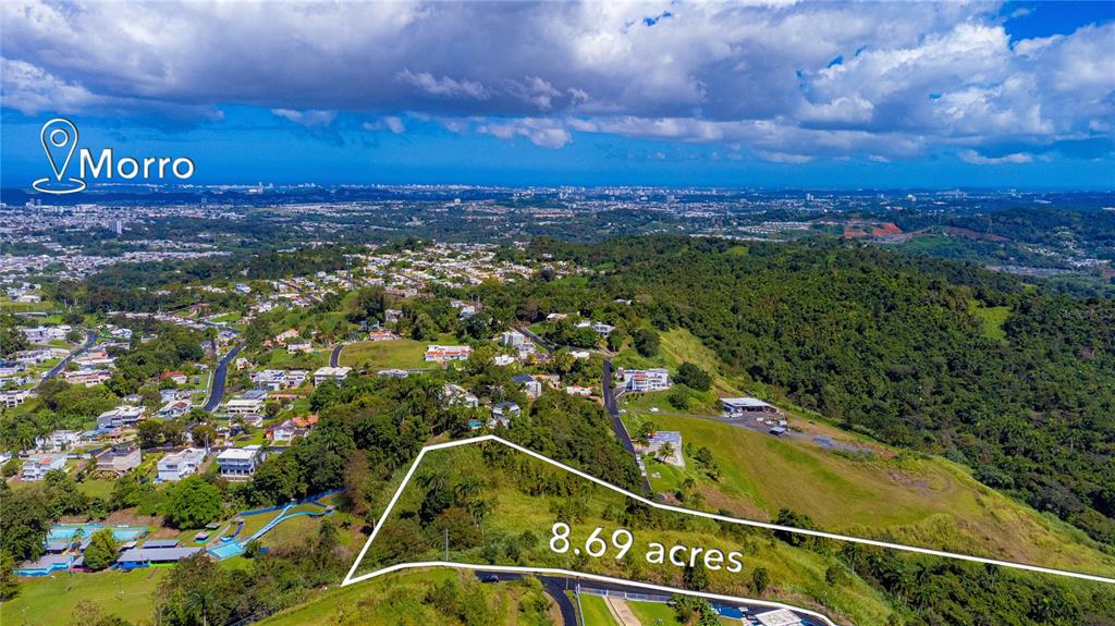 An aerial view shows a large, grassy plot of land outlined in white on a hillside — BO. MINILLAS CAMINO PABLO SILVA, BAYAMON, PR