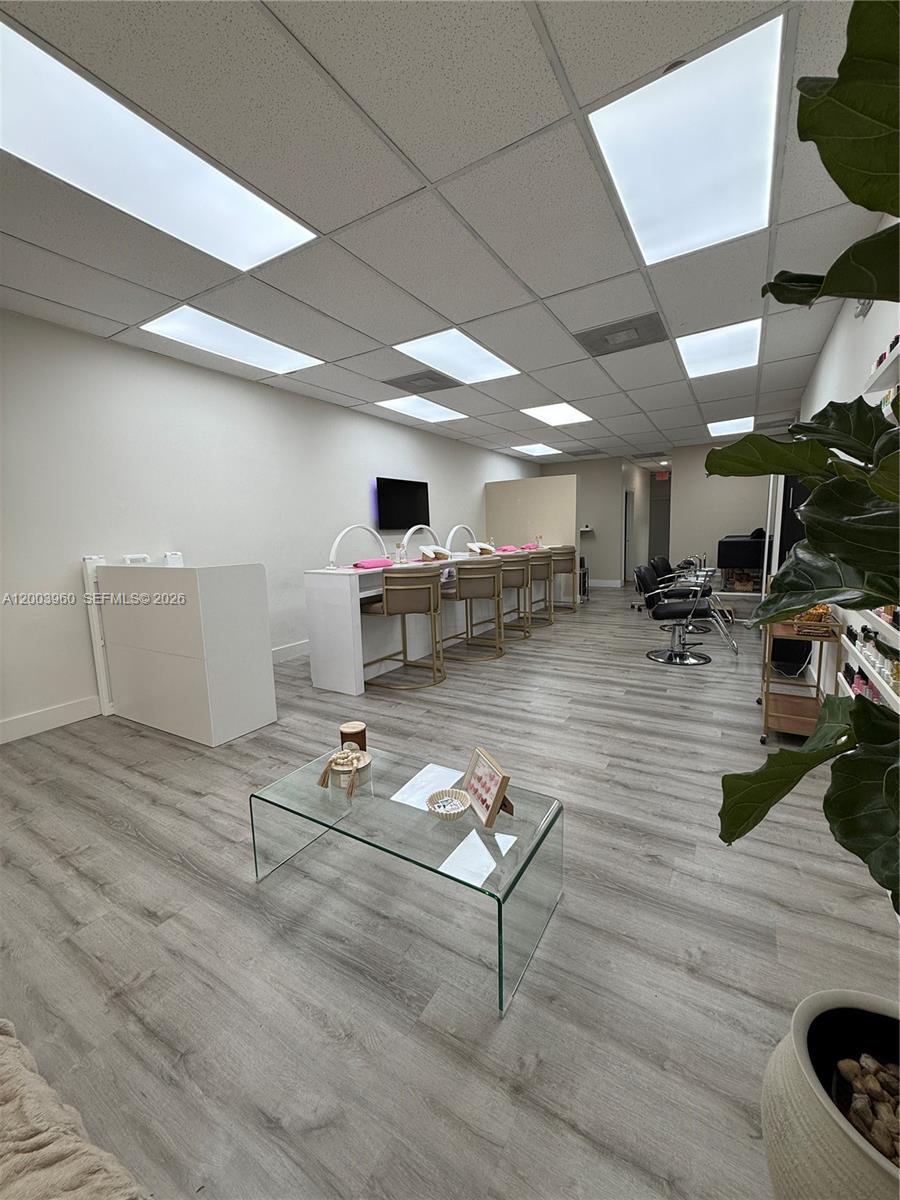 This nail salon features a glass coffee table, manicure stations, and wood-look flooring — CORAL GABLES, FL