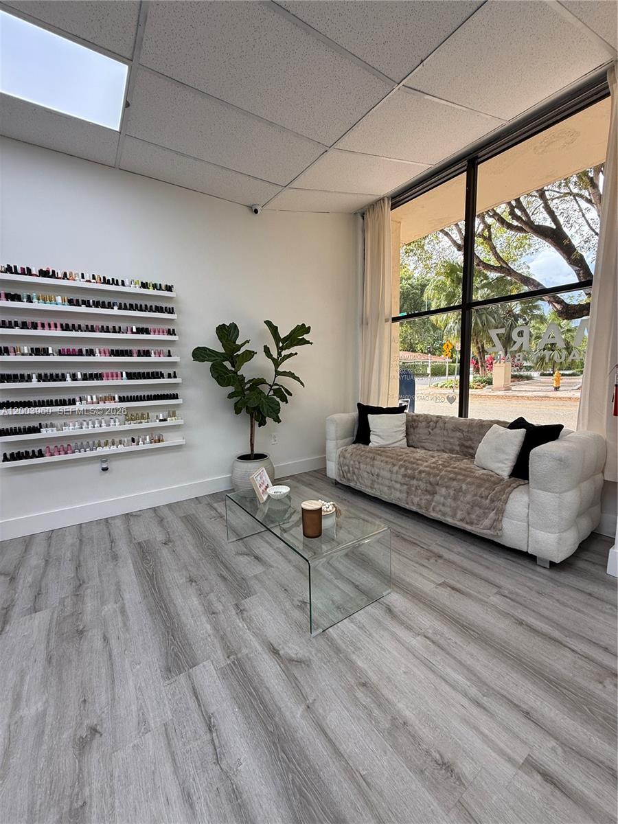 A waiting area features a glass coffee table, a sofa, and wall-mounted nail polish shelves — CORAL GABLES, FL
