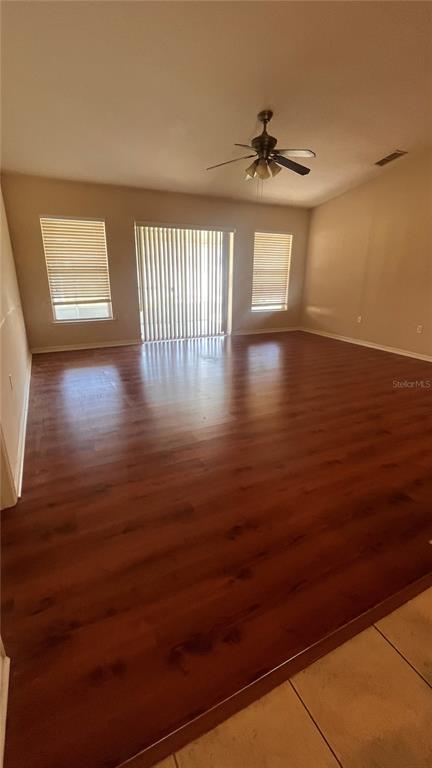 A living room features wood-look flooring, a ceiling fan, and sliding glass doors with blinds — 451 PEACE COURT, KISSIMMEE, FL