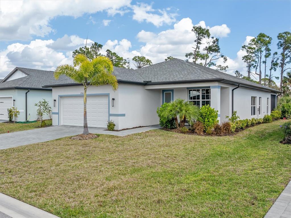 A single-story house with a white stucco exterior, a two-car garage, and a palm tree — 1736 SUNSET PRESERVE WAY, PORT CHARLOTTE, FL
