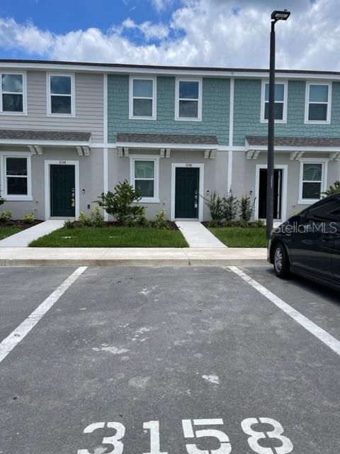 A row of townhouses with dark doors and a parking space in the foreground — 3158 SKYLINE LOOP, KISSIMMEE, FL
