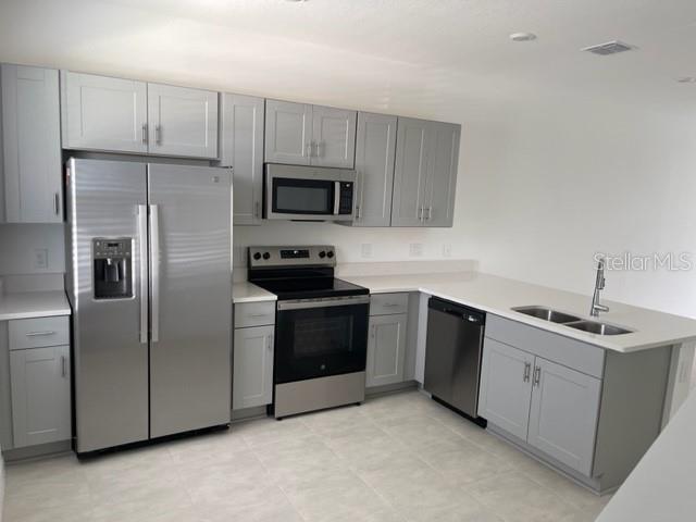 A kitchen features light gray cabinets, stainless steel appliances, and a double-basin sink — 3158 SKYLINE LOOP, KISSIMMEE, FL