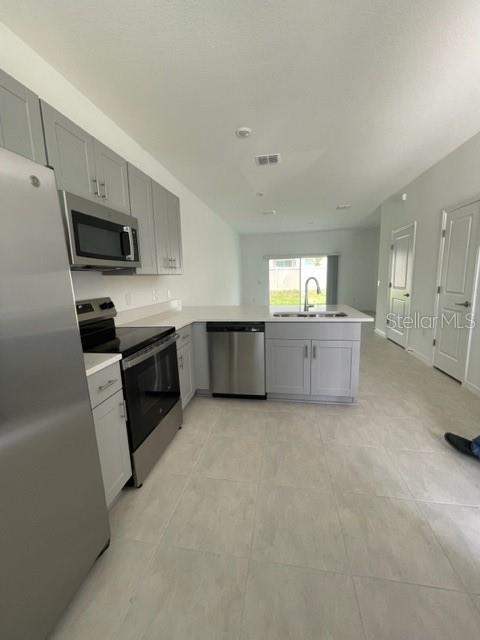 A modern kitchen features light gray cabinets, stainless steel appliances, and light-colored tile flooring — 3158 SKYLINE LOOP, KISSIMMEE, FL