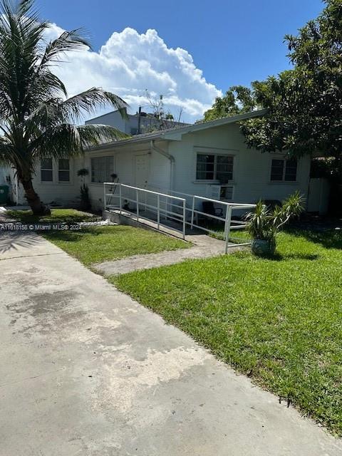 A white single-story house features a metal wheelchair ramp leading to the front entrance — 470 NW 26th Ave, Miami FL 33125, MIAMI, FL