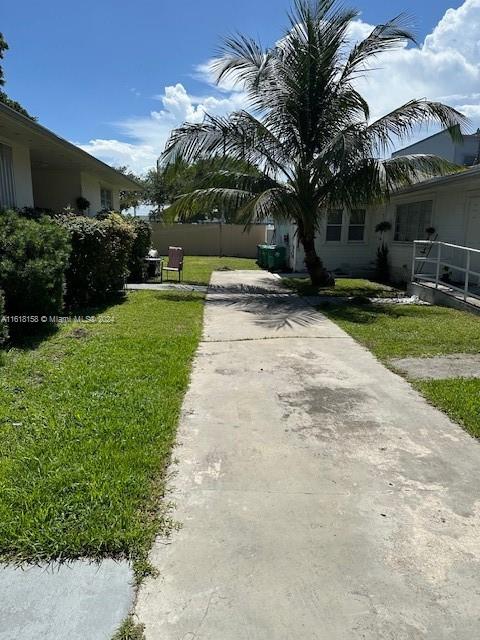 A concrete driveway leads toward a house with a palm tree in the front yard — 470 NW 26th Ave, Miami FL 33125, MIAMI, FL