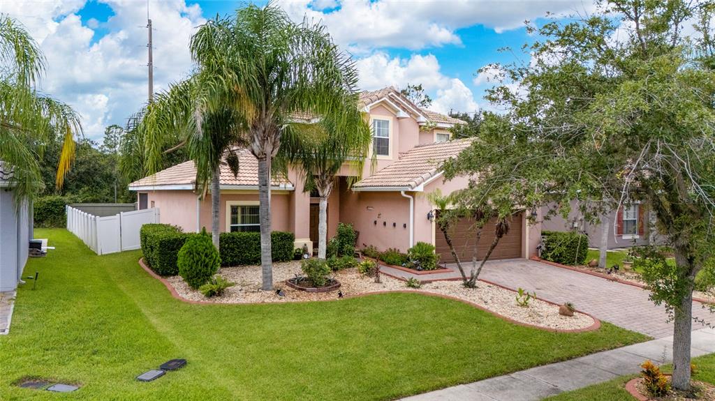 A two-story, peach-colored suburban house with a tile roof, palm trees, and a paved driveway — 4089 NAVIGATOR WAY, KISSIMMEE, FL
