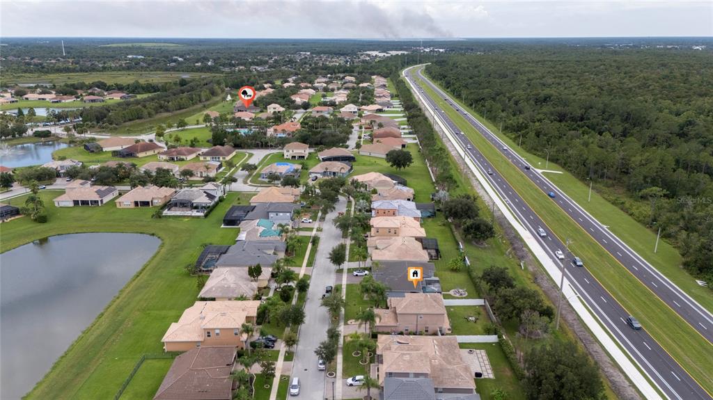 An aerial view shows a residential neighborhood with houses, a lake, and a nearby highway — 4089 NAVIGATOR WAY, KISSIMMEE, FL