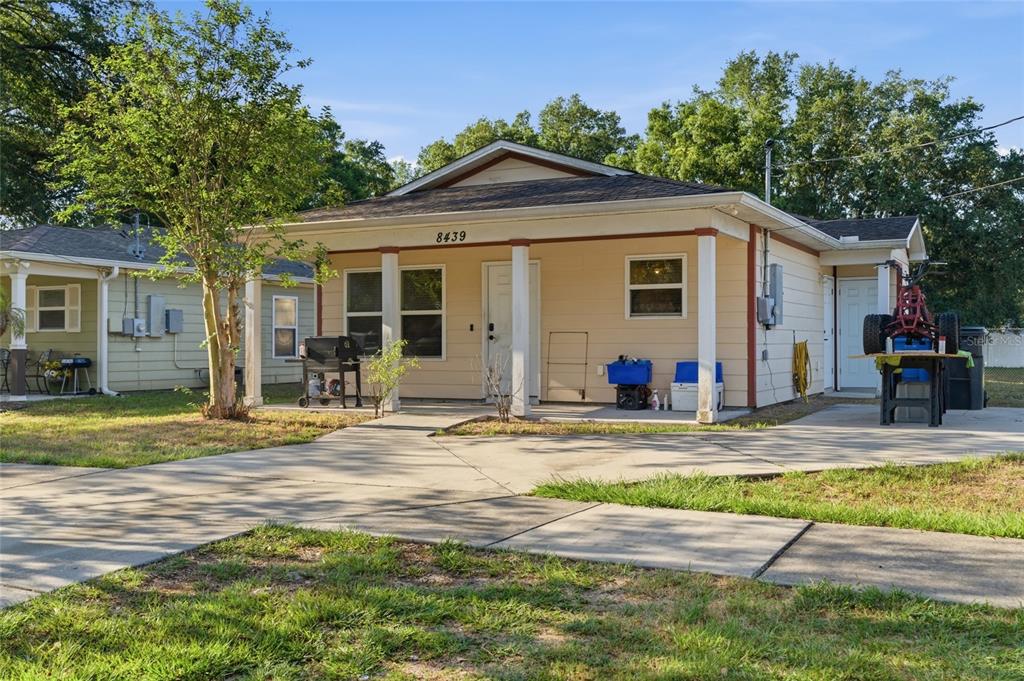 A single-story house with a covered front porch, light siding, and a concrete driveway — 8439 RADIO LANE, TAMPA, FL