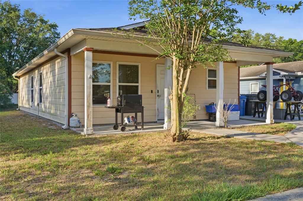 A single-story house with light yellow siding, a covered front porch, and a small tree — 8439 RADIO LANE, TAMPA, FL