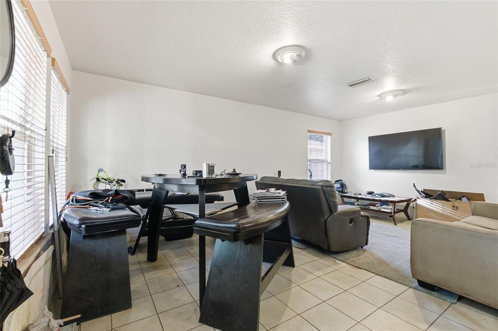 A living room with tile flooring, a dining set, and a wall-mounted television — 8439 RADIO LANE, TAMPA, FL