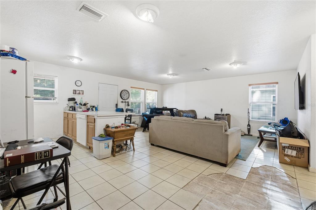 A living room and kitchen area with tile flooring, a sofa, and a kitchen island — 8439 RADIO LANE, TAMPA, FL