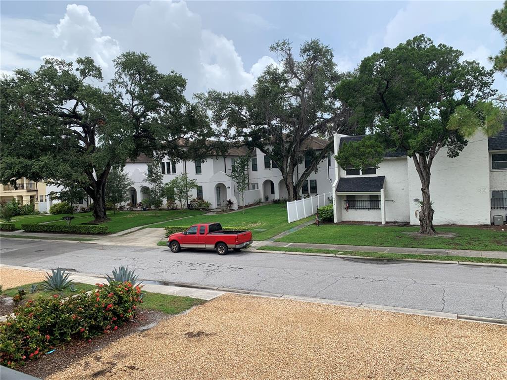 A red pickup truck is parked on a street in front of white townhouses — 4611 W FIG STREET UNIT 210, TAMPA, FL