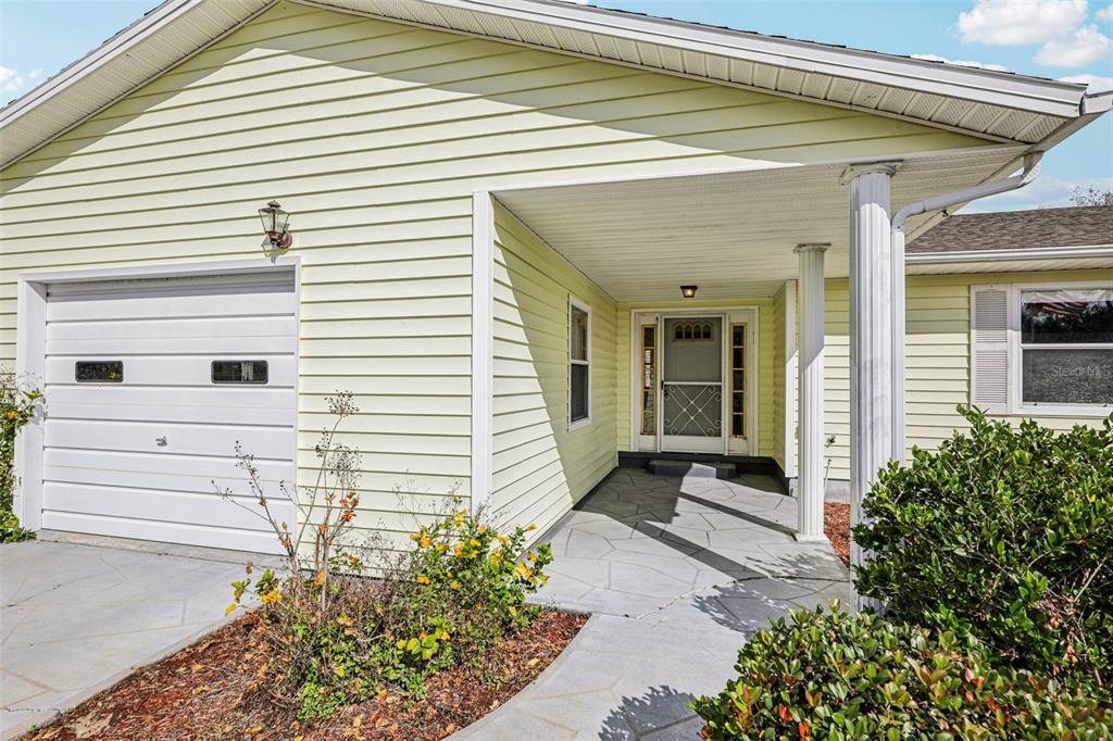 A pale yellow house exterior features a garage, a covered entryway, and a stone walkway — 510 GALLOWAY COURT, LEESBURG, FL