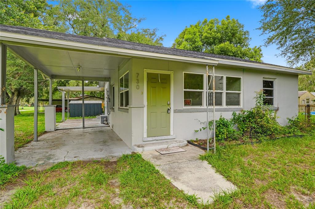 A single-story house with a light gray exterior, a green front door, and a carport — 730 WESTOVER PARKWAY, BARTOW, FL