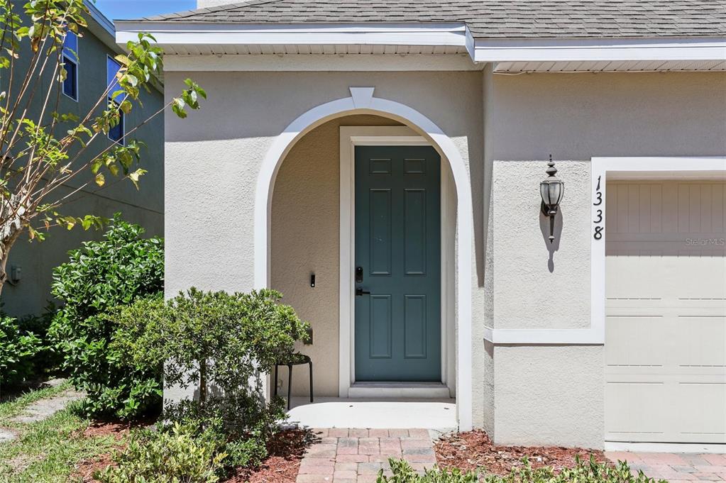 The exterior of a house features a teal front door under an arched entryway — 1338 RILEY CIRCLE, DELAND, FL