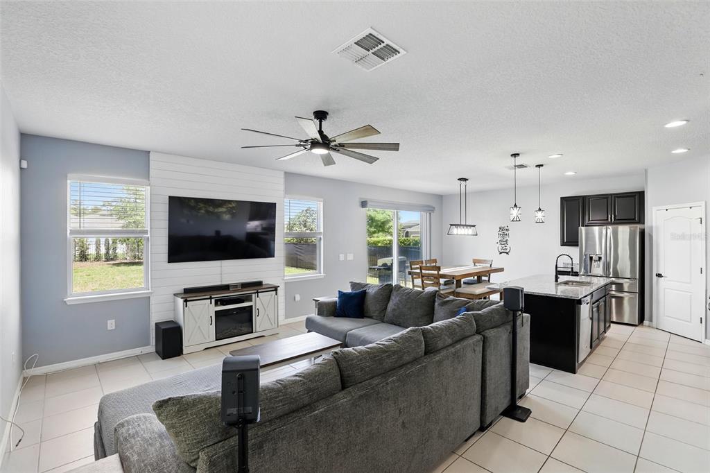 An open-concept living room and kitchen featuring a shiplap accent wall and tile flooring — 1338 RILEY CIRCLE, DELAND, FL