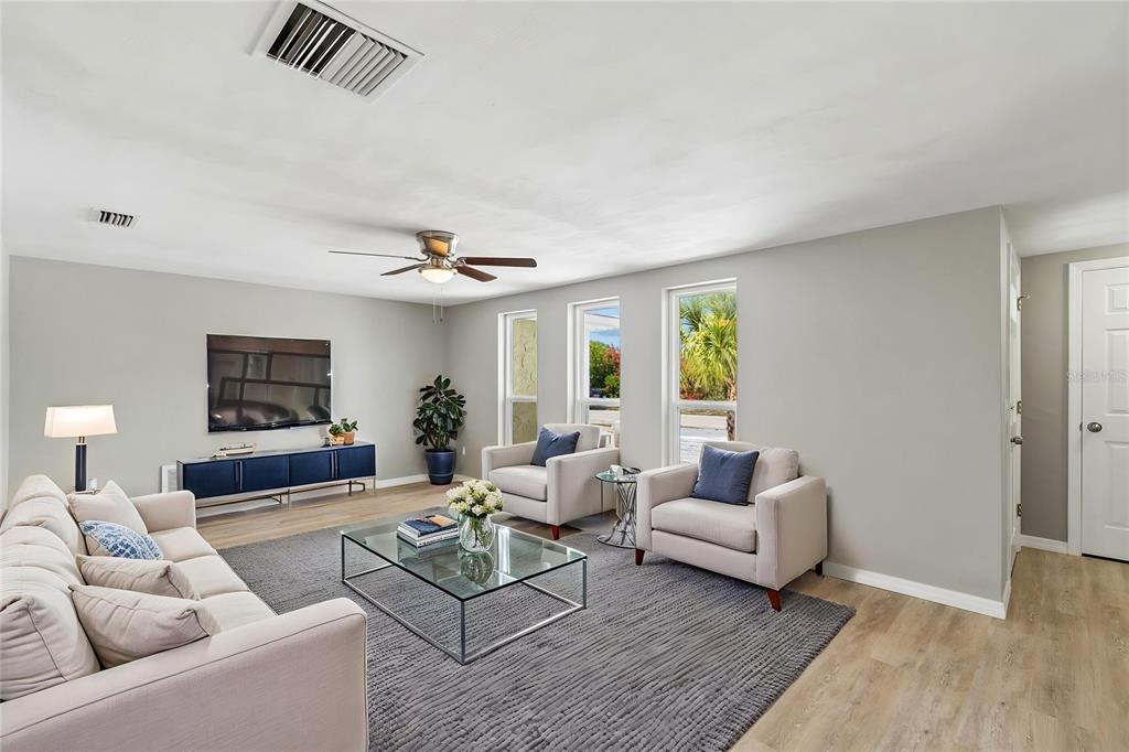 A living room features light gray walls, a gray area rug, and three neutral-toned chairs — 11130 TAMARIX AVE, PORT RICHEY, FL