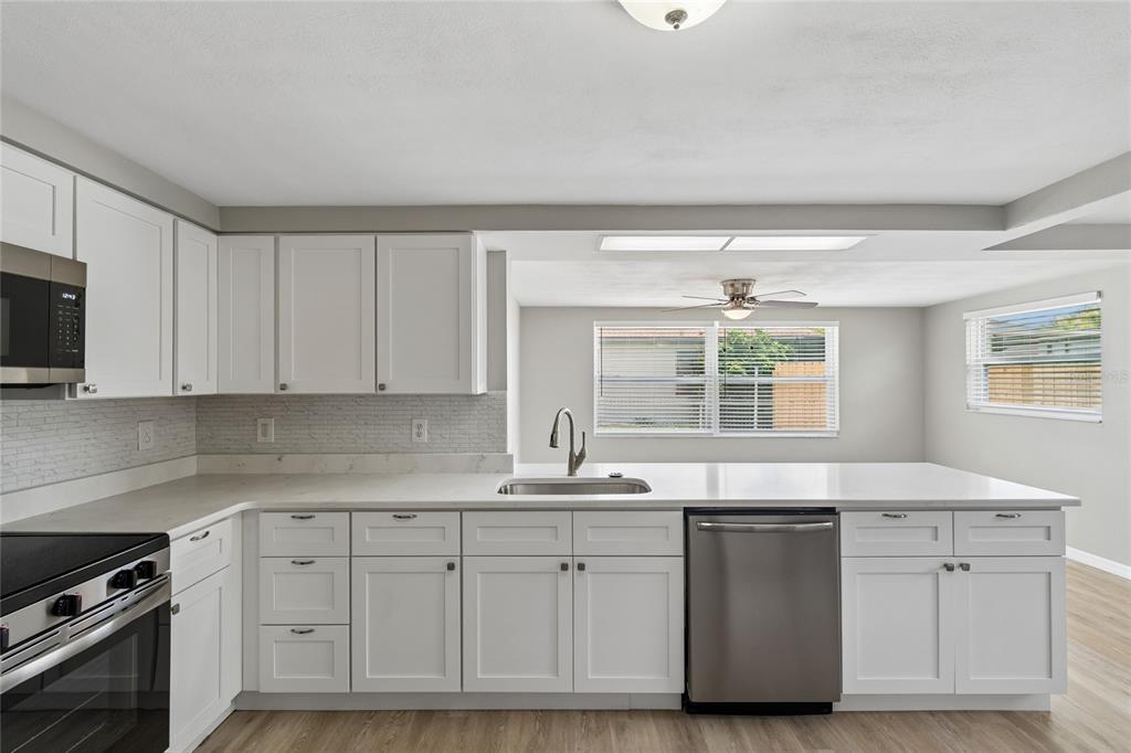 A modern kitchen features white cabinets, stainless steel appliances, and a white quartz countertop — 11130 TAMARIX AVE, PORT RICHEY, FL
