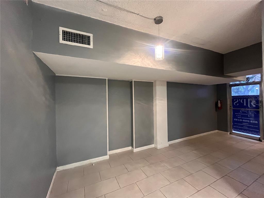 An interior room features gray walls, a tiled floor, a drop ceiling, and a glass door — 324 4TH STREET NW, WINTER HAVEN, FL