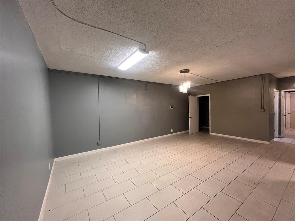 An empty room features gray walls, a tiled floor, and exposed conduit lighting — 324 4TH STREET NW, WINTER HAVEN, FL