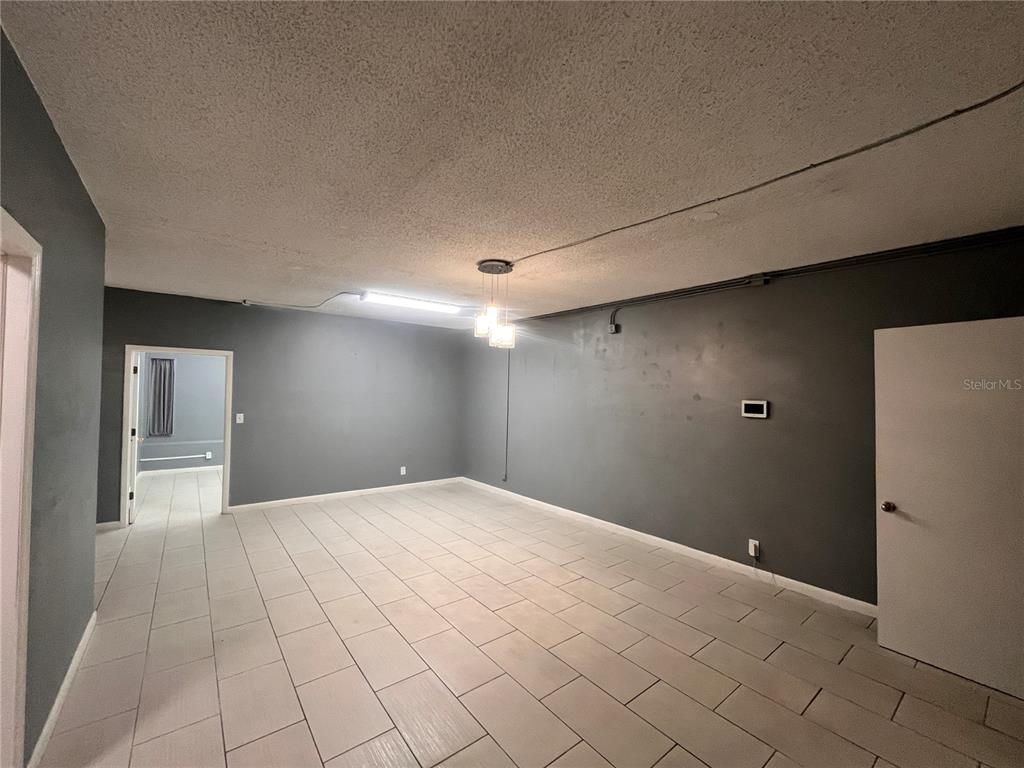 A room with dark gray walls, light tile flooring, and a textured ceiling — 324 4TH STREET NW, WINTER HAVEN, FL