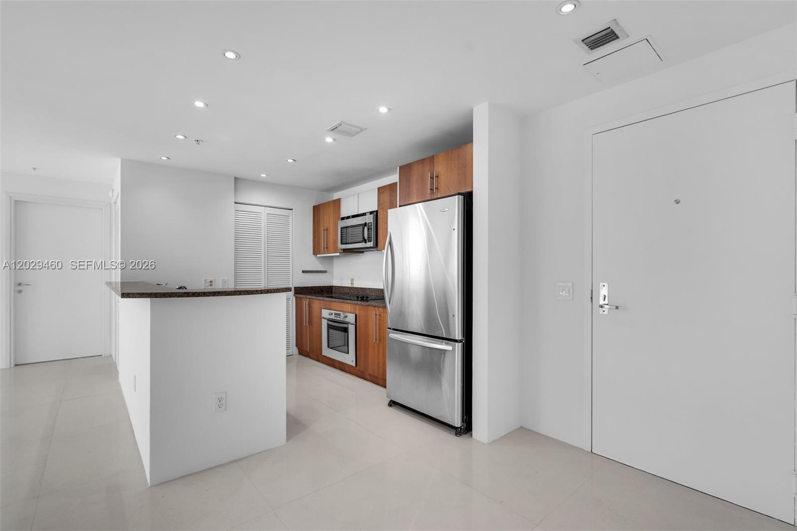 A kitchen features wood cabinets, stainless steel appliances, and a granite-topped breakfast bar — 300 S Biscayne Blvd # 3702, Miami FL 33131, MIAMI, FL
