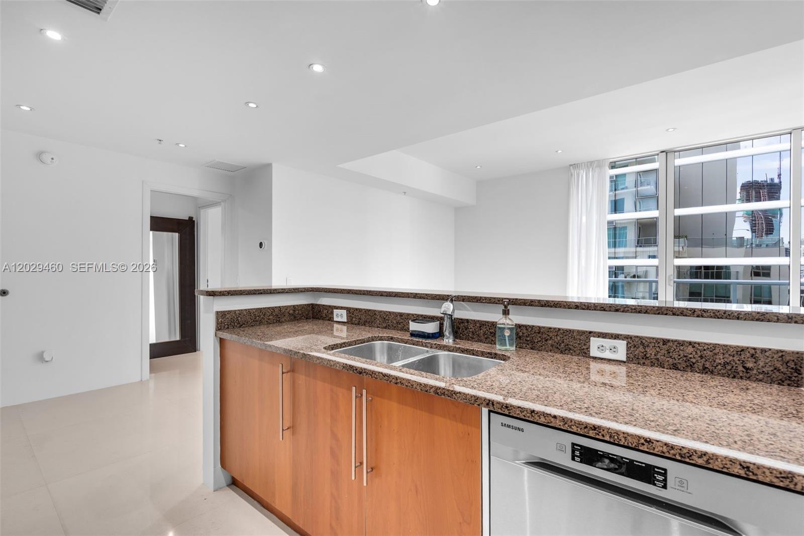 A kitchen features wood cabinets, granite countertops, a stainless steel dishwasher, and a double sink — 300 S Biscayne Blvd # 3702, Miami FL 33131, MIAMI, FL