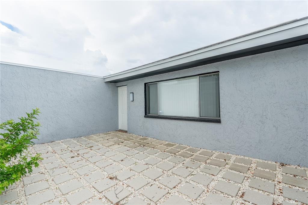 A gray stucco exterior wall features a white door and a large rectangular window — 4016 GRAYTON DRIVE, NEW PORT RICHEY, FL