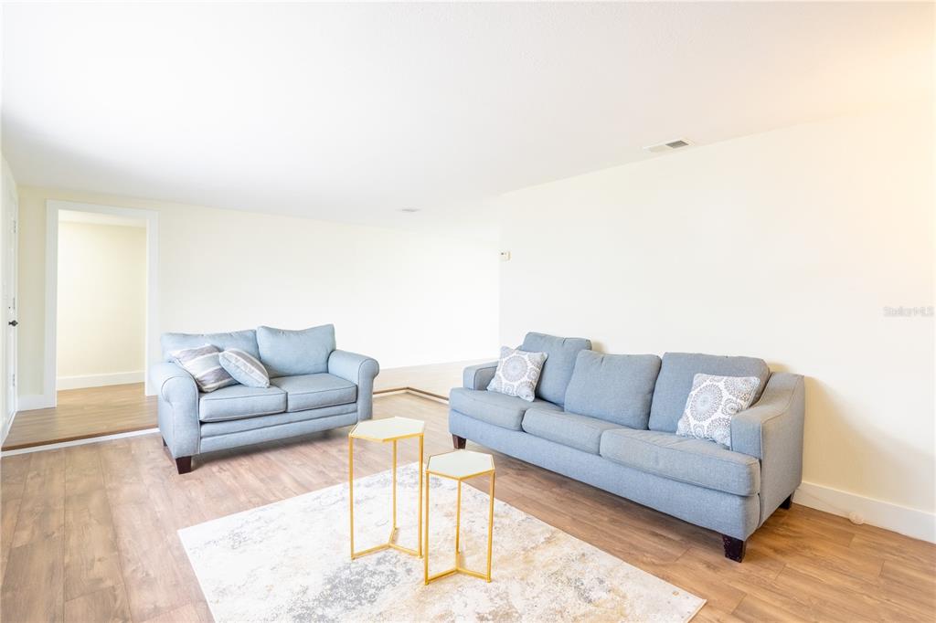 A living room features light wood flooring, two blue sofas, and two small gold tables — 4016 GRAYTON DRIVE, NEW PORT RICHEY, FL