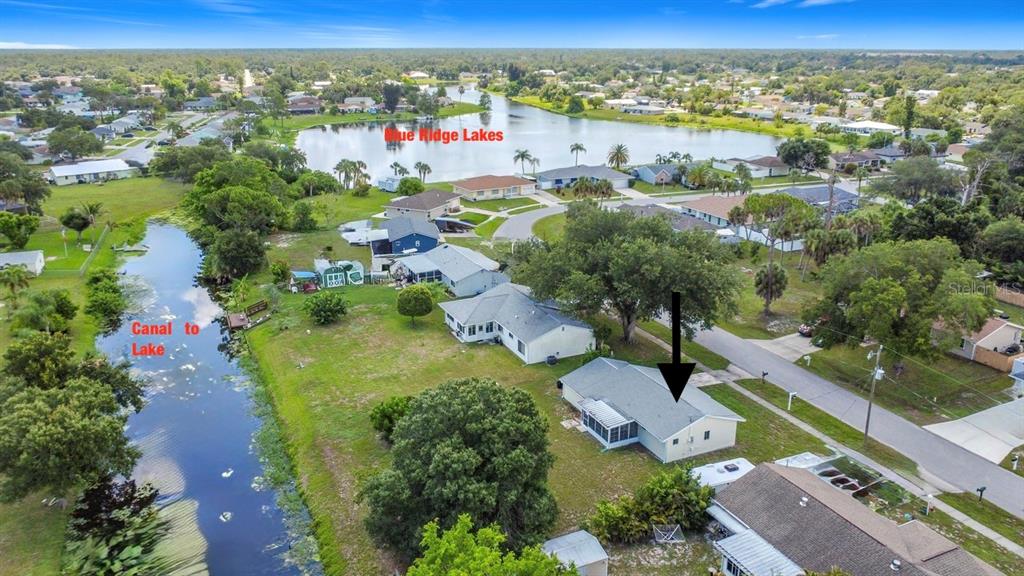 An aerial view shows a residential house with a screened porch near a canal and lake — 4804 BATCHELOR AVENUE, NORTH PORT, FL