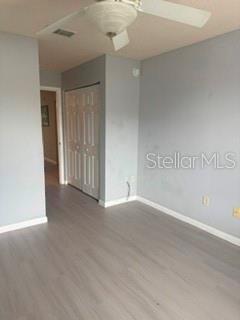 A bedroom with light gray walls, wood-look flooring, a ceiling fan, and a white closet — 11313 SW 95TH CIRCLE, OCALA, FL