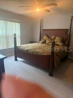 A bedroom features a large wooden four-poster bed and a window with vertical blinds — 11313 SW 95TH CIRCLE, OCALA, FL