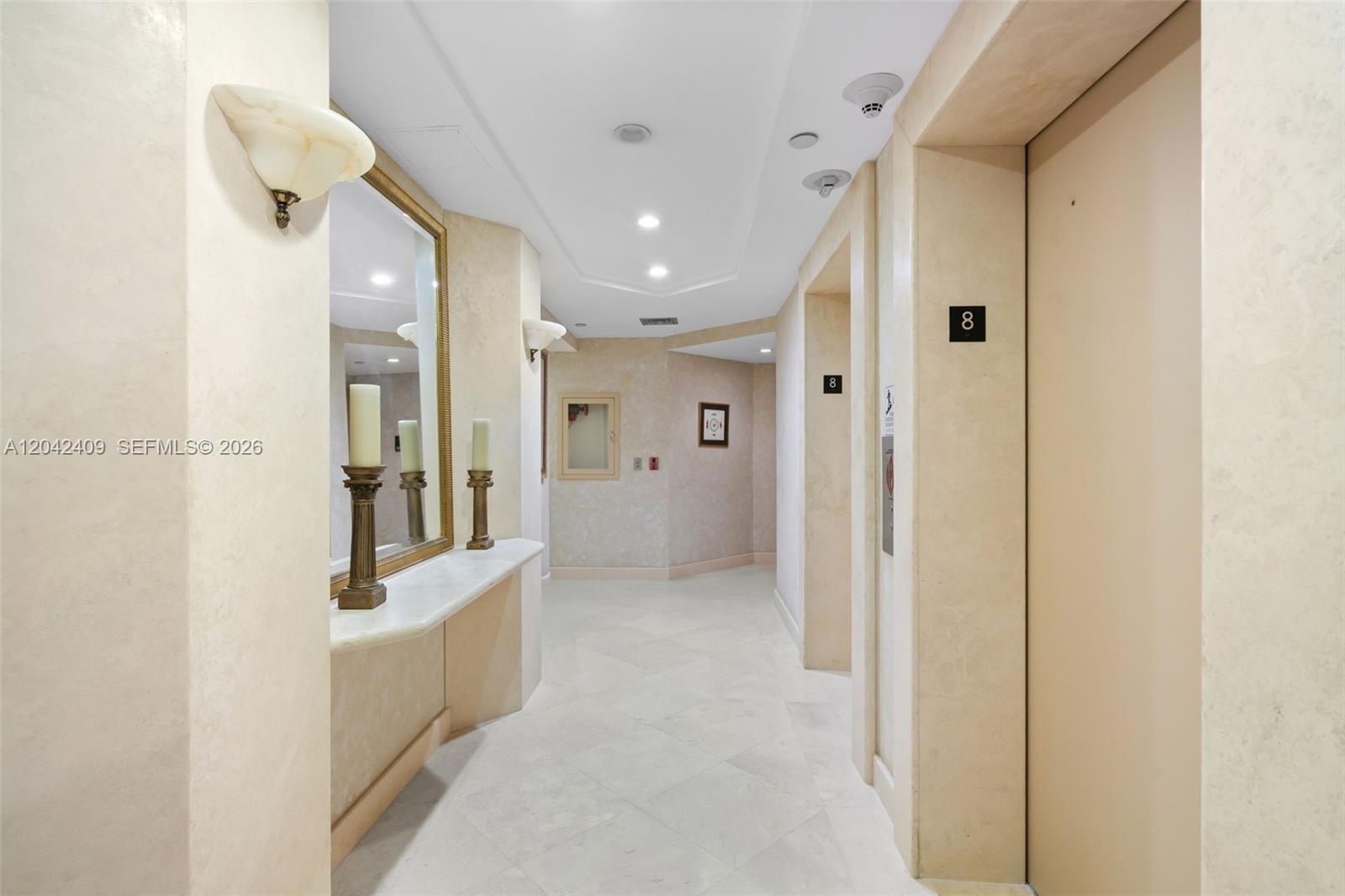 A hallway features light-colored tile floors, beige walls, a mirror, and elevator doors — 1500 S Ocean Blvd # 804, Boca Raton FL 33432, BOCA RATON, FL