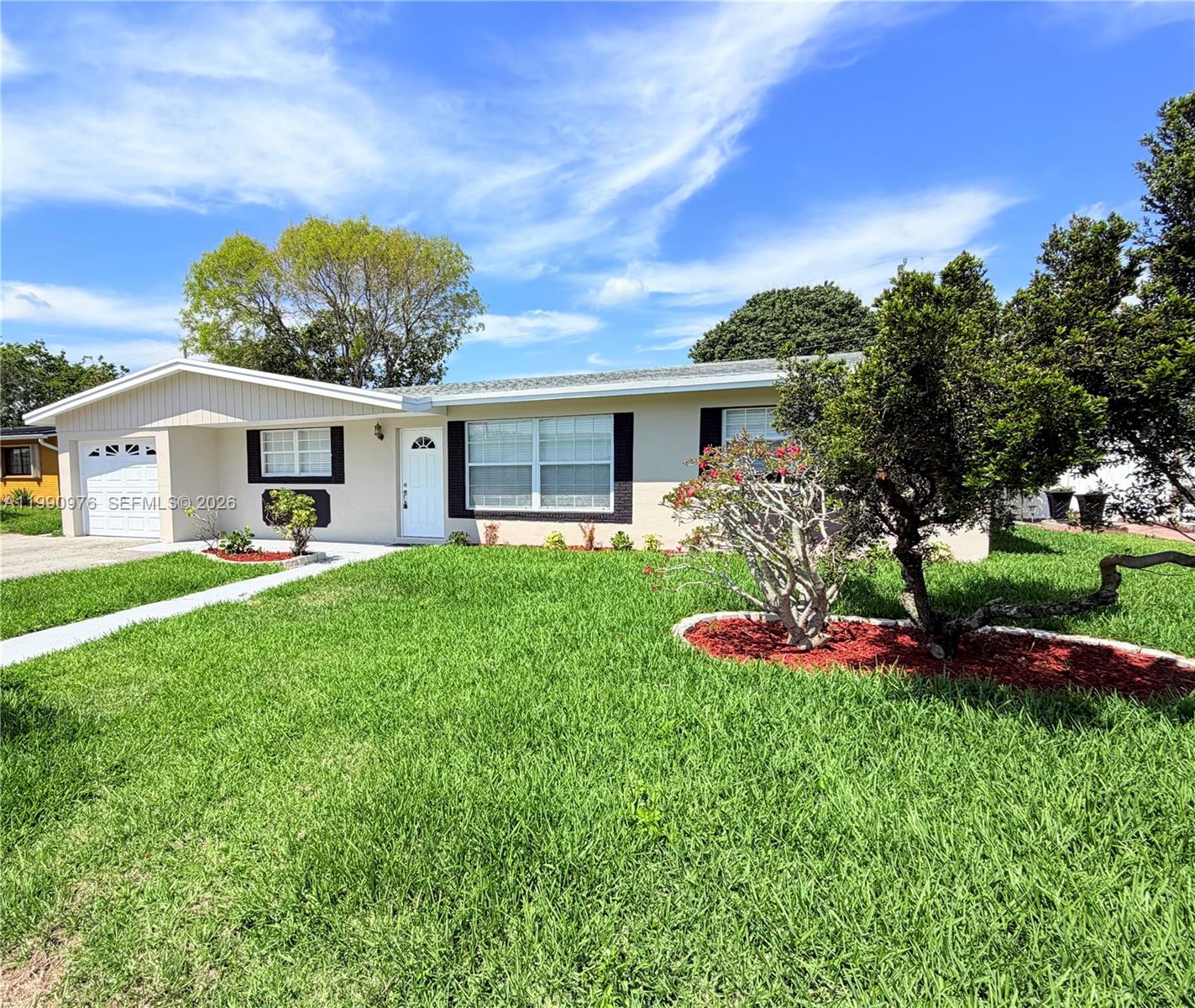 A single-story house with a white garage, beige exterior, and a manicured front lawn — 4731 NW 11th St, Lauderhill FL 33313, LAUDERHILL, FL