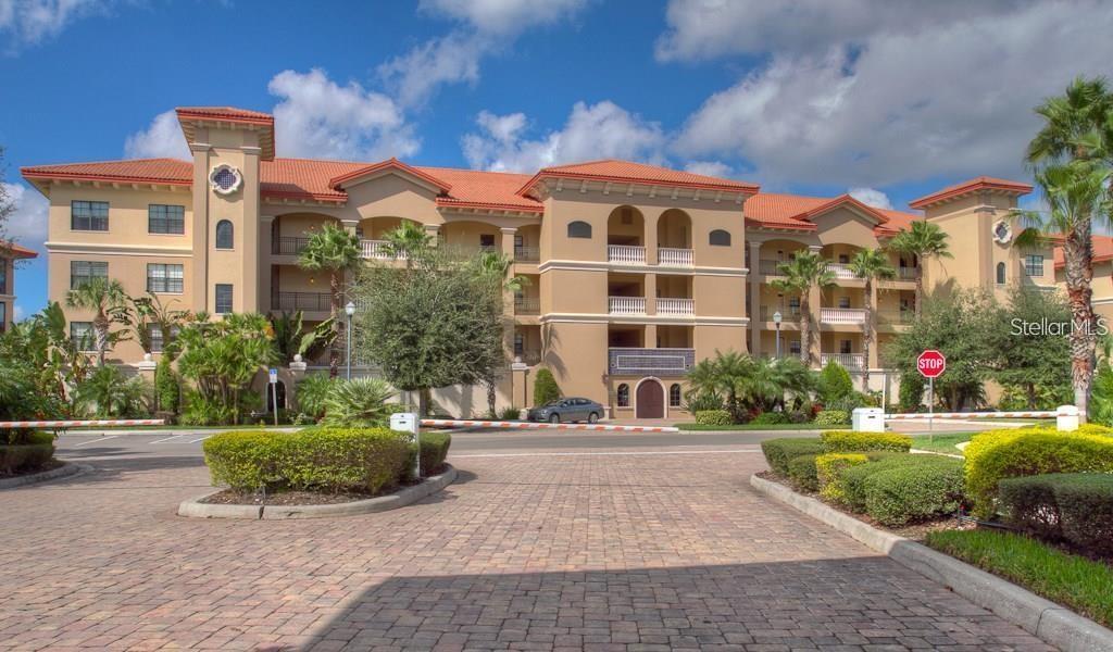A multi-story Mediterranean-style apartment building features a terracotta tile roof and a paved entrance — 7710 LAKE VISTA COURT UNIT 205, LAKEWOOD RANCH, FL