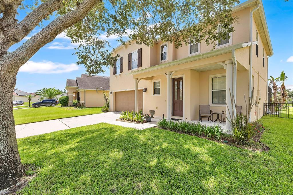 A two-story beige house with a front porch, a two-car garage, and a grassy yard — 3432 PERCHING ROAD, ST CLOUD, FL