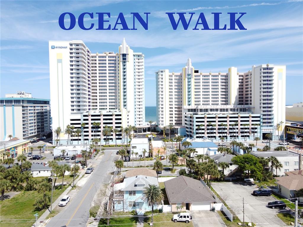 An aerial view shows the Ocean Walk resort towers overlooking a street and nearby houses — 300 N ATLANTIC AVENUE UNIT 1106, DAYTONA BEACH, FL