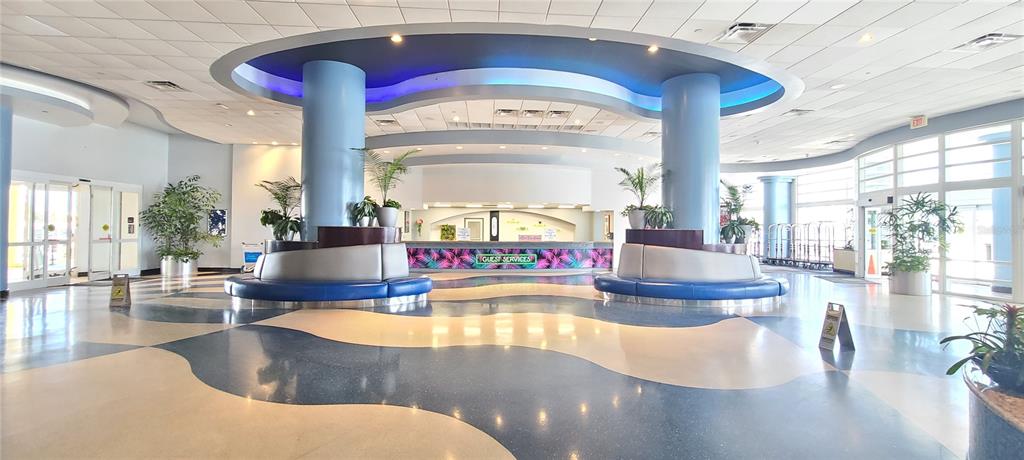 A spacious hotel lobby features blue curved pillars, a guest services desk, and patterned flooring — 300 N ATLANTIC AVENUE UNIT 1106, DAYTONA BEACH, FL