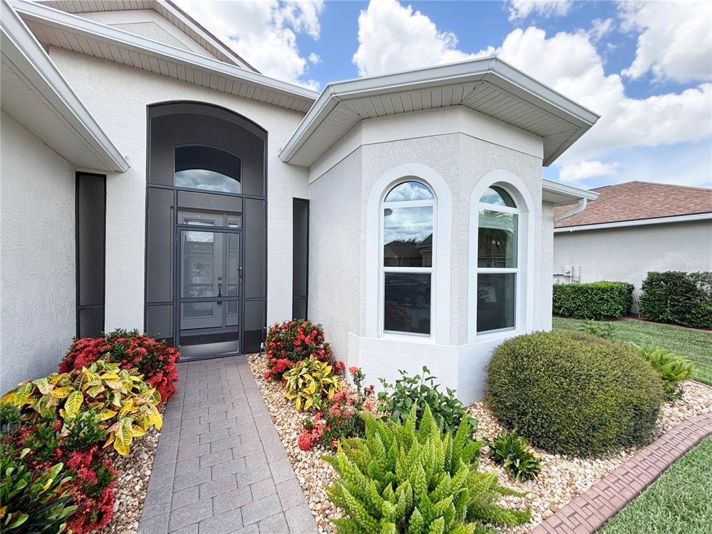 A paved walkway leads to the front entrance of a house with white stucco walls — 5553 HOGAN LANE, WINTER HAVEN, FL