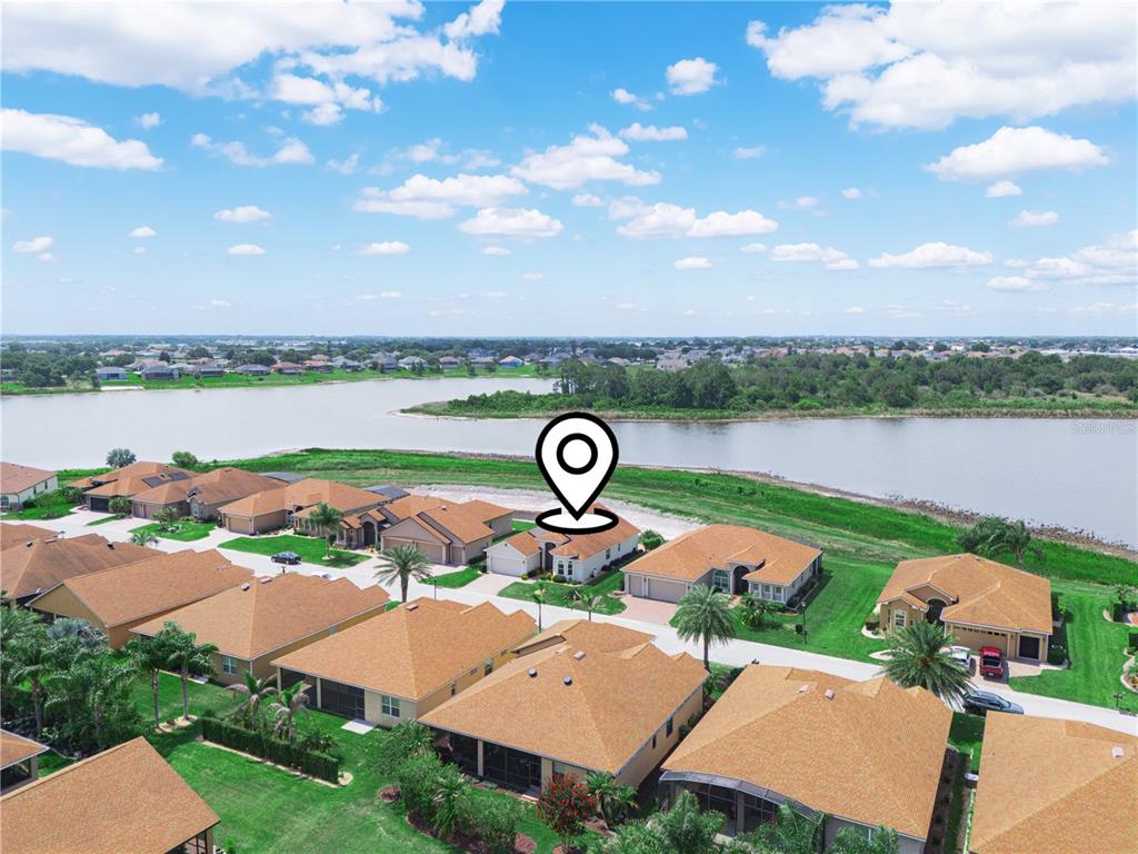 An aerial view shows a residential neighborhood with houses situated along a large lake — 5553 HOGAN LANE, WINTER HAVEN, FL