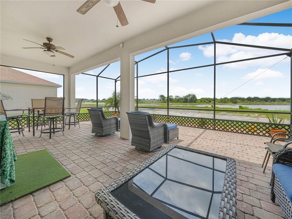 A covered patio with brick pavers, outdoor furniture, and a screened view of a lake — 5553 HOGAN LANE, WINTER HAVEN, FL