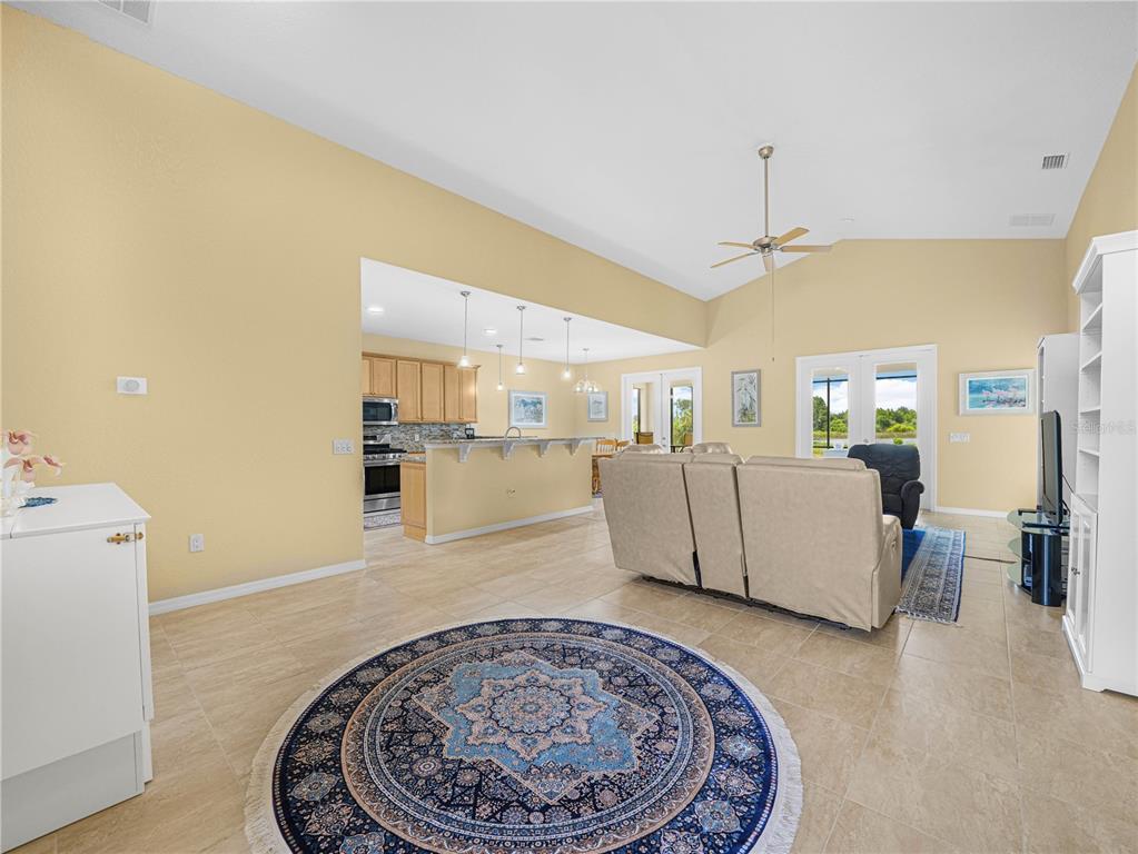 A spacious open-concept living room and kitchen area with tile flooring and vaulted ceilings — 5553 HOGAN LANE, WINTER HAVEN, FL