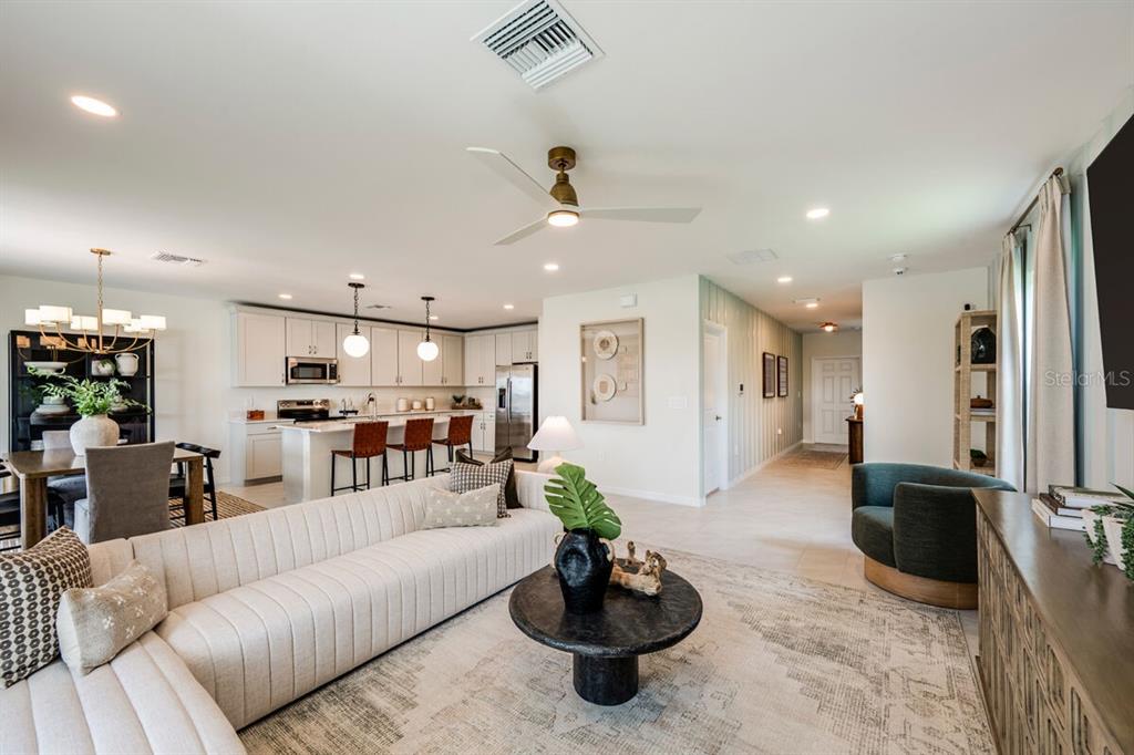 An open-concept living room and kitchen featuring a large sectional, dining area, and island seating — 13688 LOREDO WAY, PUNTA GORDA, FL