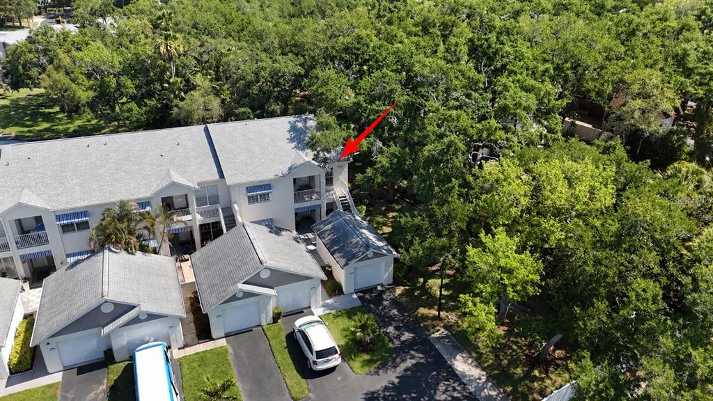An aerial view shows a multi-story residential building with attached garages and surrounding trees — 11303 SHIPWATCH LANE UNIT 1865, LARGO, FL