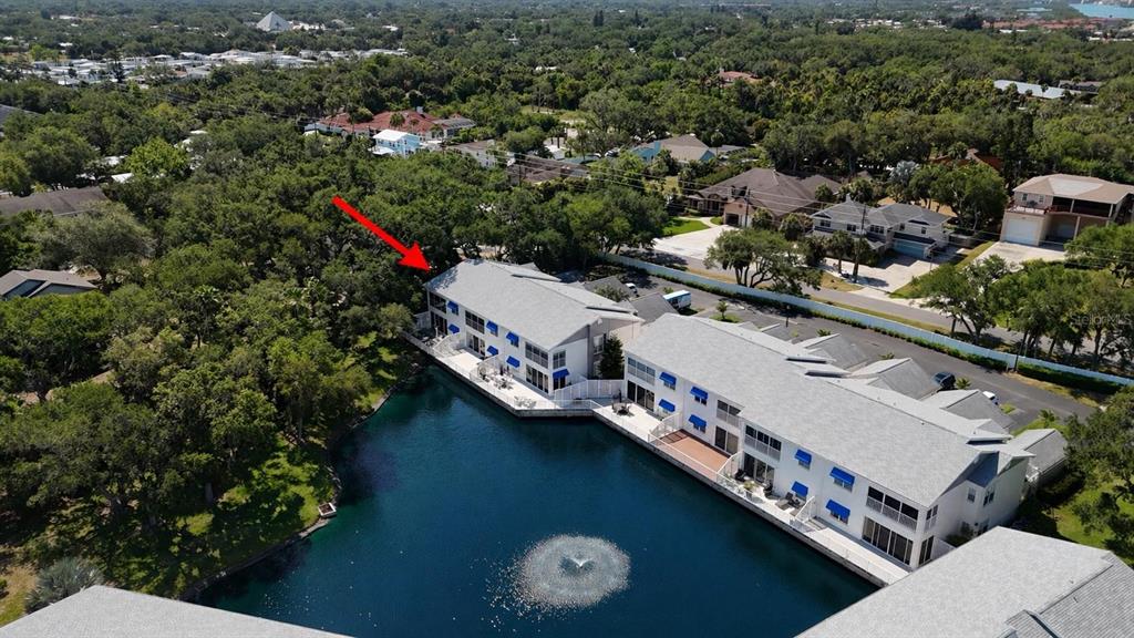An aerial view shows two multi-story apartment buildings situated along the edge of a pond — 11303 SHIPWATCH LANE UNIT 1865, LARGO, FL