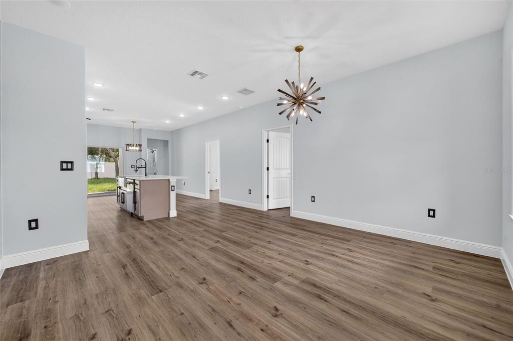 An open-concept living area features light gray walls, wood-look flooring, and a modern sputnik chandelier — 1854 SUPERIOR COURT, POINCIANA, FL
