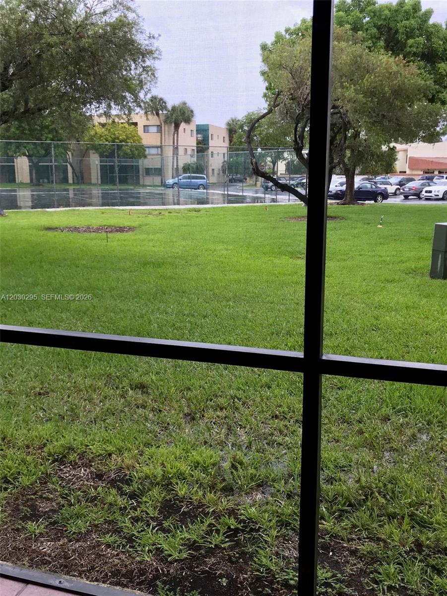 A view from a screened-in porch looks out over a grassy lawn and parking lot — 8015 SW 107th Ave # 120, Miami FL 33173, MIAMI, FL