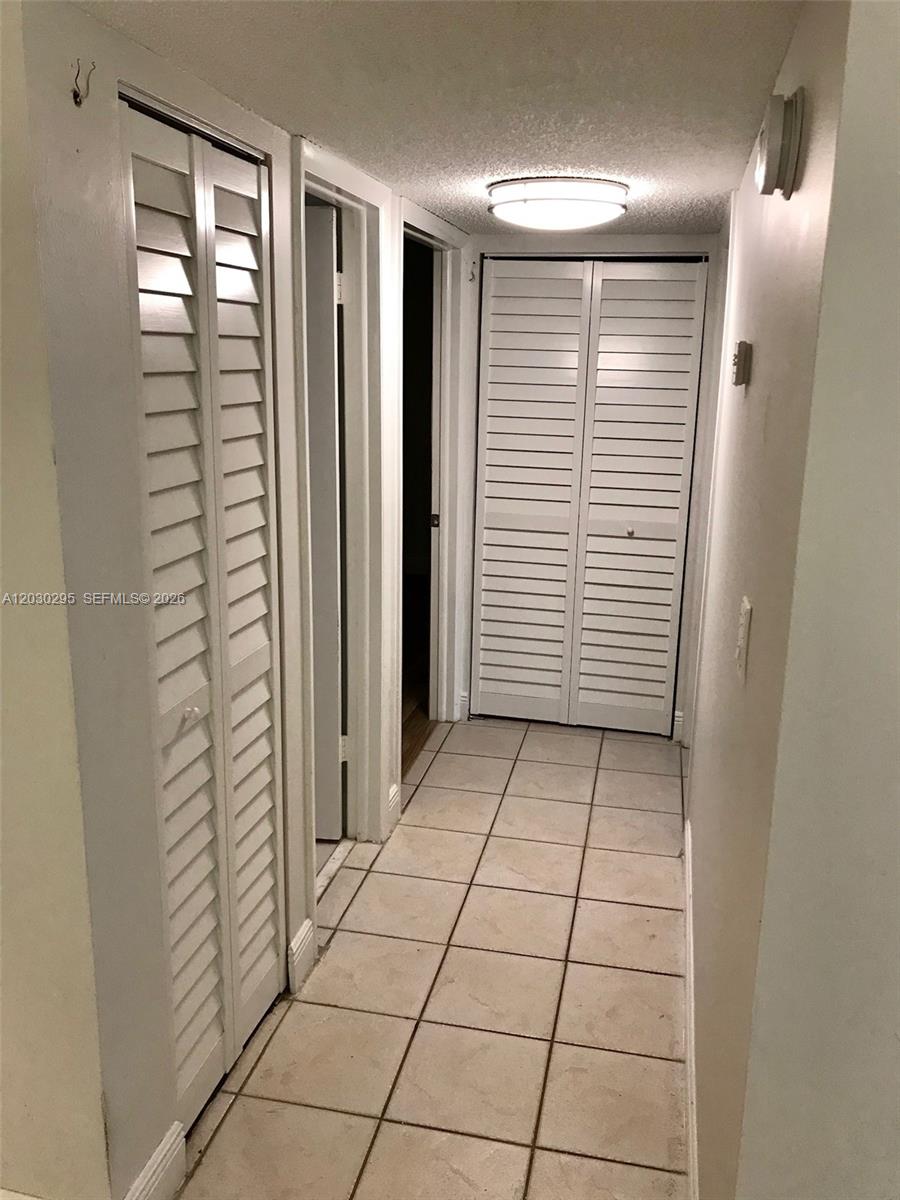 A hallway features white louvered closet doors, tiled flooring, and a flush-mount ceiling light — 8015 SW 107th Ave # 120, Miami FL 33173, MIAMI, FL