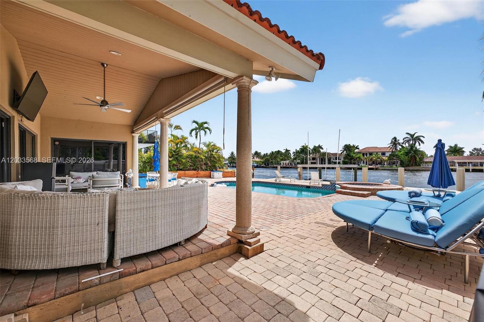 A covered patio overlooks a swimming pool, hot tub, and a canal with boat docks — 317 S Riverside Dr, Pompano Beach FL 33062, POMPANO BEACH, FL